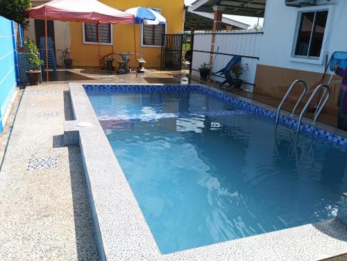 a swimming pool with blue water in a yard at TWIN TWO Homestay in Kepala Batas