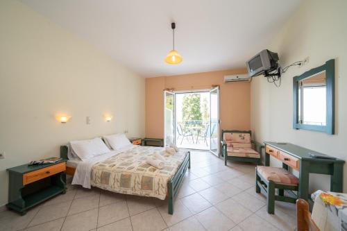 a bedroom with a bed and a desk and a tv at Milos Studios in Lourdhata