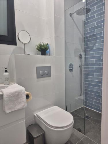 a white bathroom with a toilet and a shower at סוויטת ארגמן in Beʼer Ora