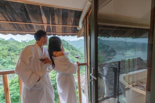 a man and a woman standing on a balcony with a glass of wine at Gia Trang Heian Hoa Binh in Hòa Bình