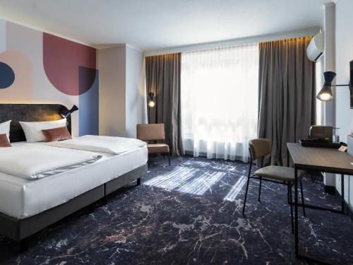 マインツにあるMercure Mainz City Centerのベッドと机があるホテルの部屋