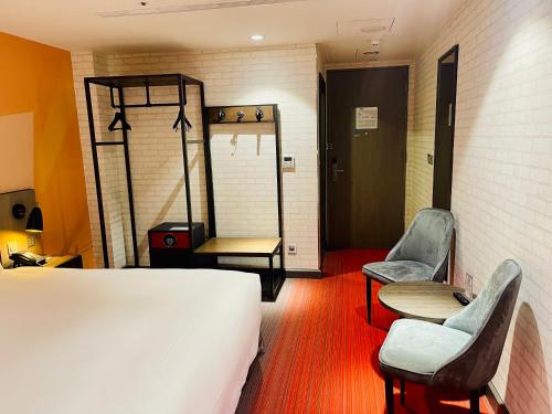 a room with a bed and two chairs and a table at T11、T12 Hotel in Houli