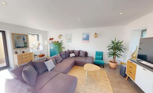 ein Wohnzimmer mit einem lila Sofa und einem TV in der Unterkunft Maison familiale entre mer et campagne in Putot-en-Bessin