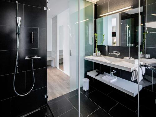 a bathroom with a shower and a sink and a mirror at Mercure Chur City West in Chur