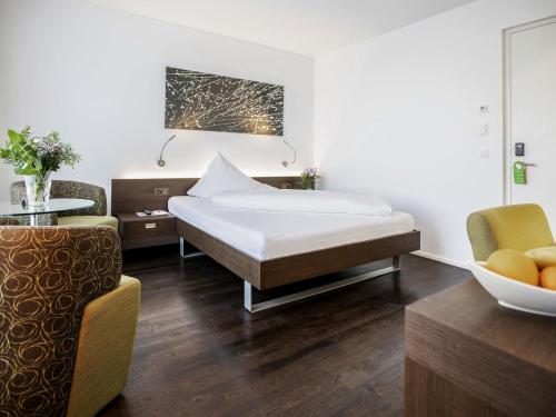 a hotel room with a bed and a chair at Mercure Chur City West in Chur