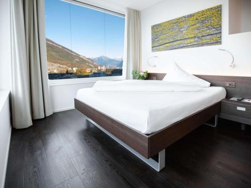 a bedroom with a large bed with a large window at Mercure Chur City West in Chur