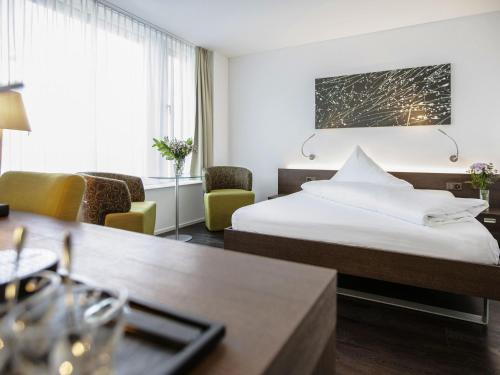 a hotel room with two beds and a table and chairs at Mercure Chur City West in Chur