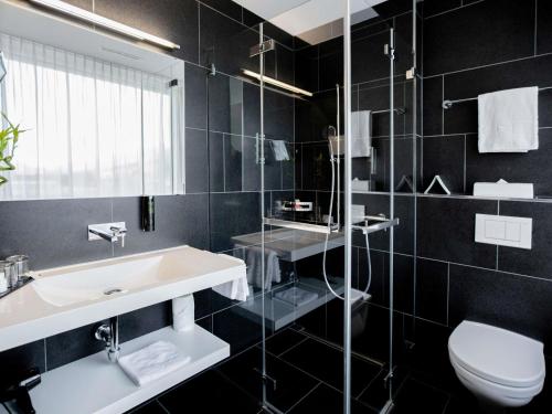 a bathroom with a sink and a toilet at Mercure Chur City West in Chur