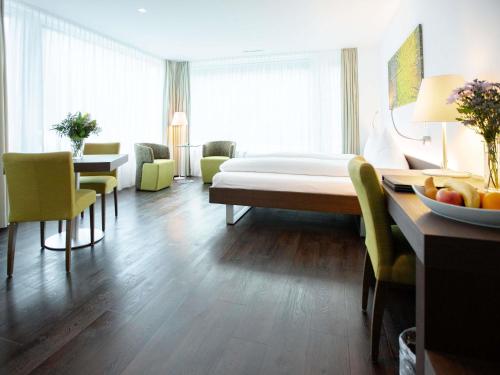 a hotel room with a bed and a table and chairs at Mercure Chur City West in Chur