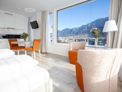 a living room with a table and chairs and a large window at Mercure Chur City West in Chur