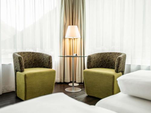 two chairs and a lamp in a hotel room at Mercure Chur City West in Chur