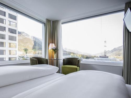 a hotel room with two beds and a large window at Mercure Chur City West in Chur