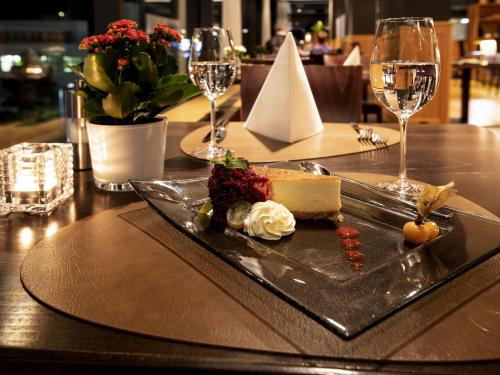 a plate of food on a table with wine glasses at Mercure Chur City West in Chur