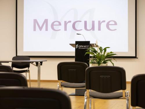 a meeting room with a screen with a presentation at Mercure Chur City West in Chur