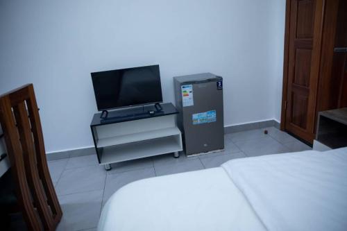 Una habitación con un televisor y una cómoda con un pequeño refrigerador. en Blue sky apartment, en Kigali