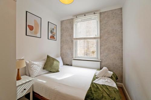 a small bedroom with a bed and a window at Imperial Argyle Square Apartment in London
