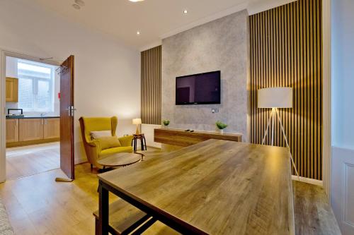 a living room with a wooden table and a tv at Imperial Argyle Square Apartment in London