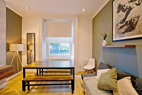 a living room with a table and a couch at Imperial Argyle Square Apartment in London