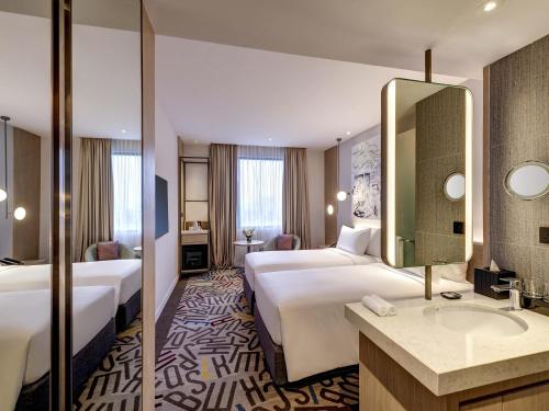 a hotel room with two beds and a sink at Mercure Kuala Lumpur Glenmarie in Shah Alam