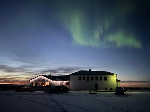 a house in the snow with cars parked in front of it at Skulagardur Country Hotel in Garður