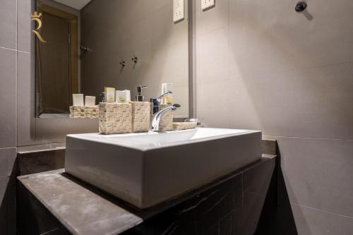 a bathroom with a white sink and a mirror at Al Vera Elegant 2BR Apartment Private Balcony in Abu Dhabi