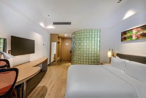a hotel room with a bed and a flat screen tv at Holiday Inn Express Haikou West Coast by IHG in Haikou