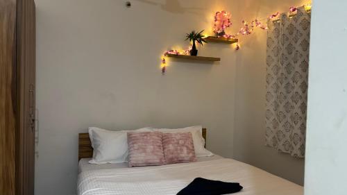 a bedroom with a bed with pink pillows and lights at Swarga Fireflies Duo in Bengaluru