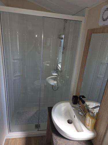 a bathroom with a shower and a white sink at 61, Stowford Gardens in Combe Martin