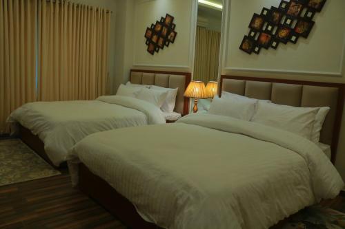 a bedroom with two beds with white sheets at Bahria Sunrise Apartments in Rawalpindi