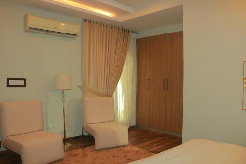 a bedroom with two white chairs and a bed at Bahria Sunrise Apartments in Rawalpindi