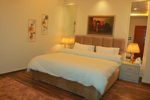 a bed in a bedroom with two lamps and a mirror at Bahria Sunrise Apartments in Rawalpindi