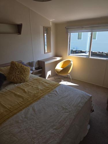 a bedroom with a bed and a chair and a window at 61, Stowford Gardens in Combe Martin