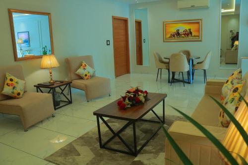 a living room with chairs and a table with flowers on it at Bahria Sunrise Apartments in Rawalpindi