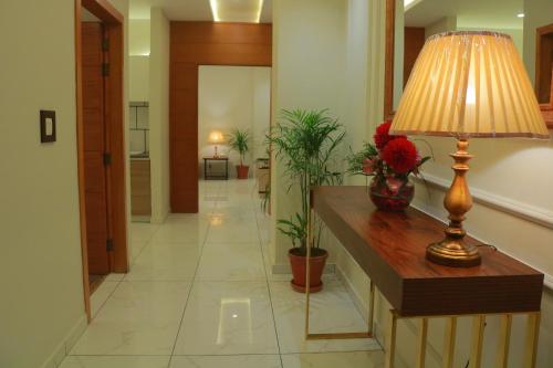 a hallway with a table with a lamp and flowers at Bahria Sunrise Apartments in Rawalpindi