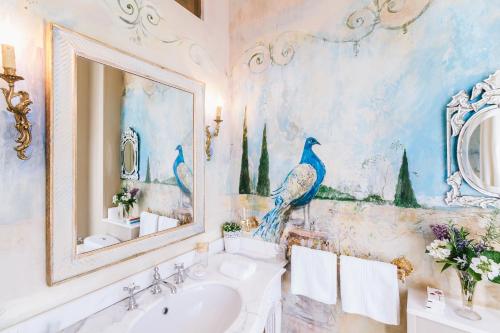un baño con una pintura de un pavo real en la pared en Château La Creuzette, en Boussac