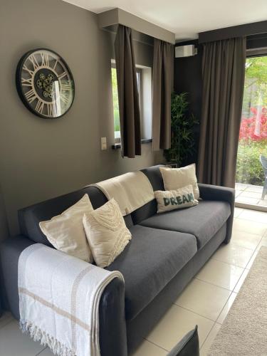 a blue couch in a living room with a clock on the wall at Durbuy Dream in Durbuy