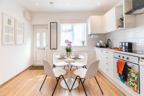 une cuisine avec des armoires blanches et une table et des chaises dans l'établissement New! Delightful 2BR Flat in Woolwich, à Plumstead