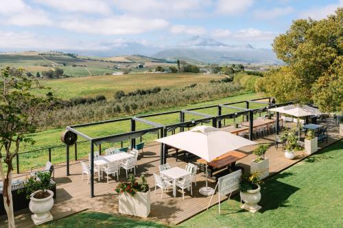 a deck with tables and chairs and a view of a field at The Salene Hotel & Apartments in Stellenbosch