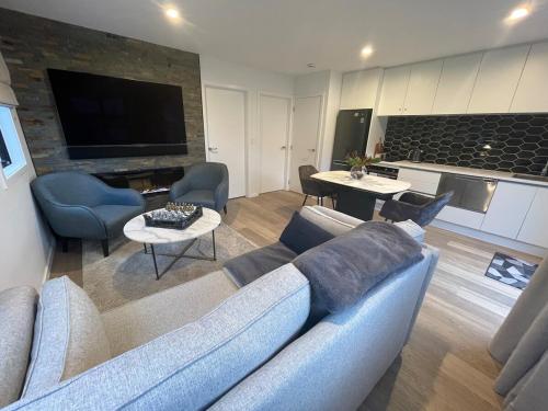 a living room with a couch and tables and a tv at Spa apartment in Queenstown in Queenstown Airport