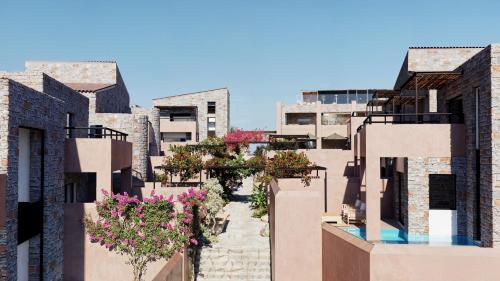 an alley with flowers in the middle of buildings at Volta Seaside Boutique Hotel in Kokkíni Khánion