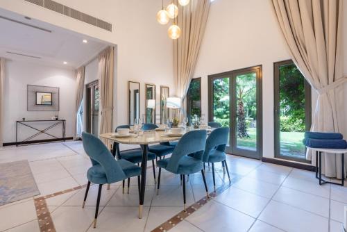 a dining room with a table and blue chairs at Luxury Beachfront Villa with Direct Beach Access, Next to Community Pool, Close to the Thrills of Aquaventure Waterpark, Canal Cove, Palm Jumeirah by Deluxe Holiday Homes in Dubai