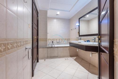a bathroom with a tub and a sink and a mirror at Luxury Beachfront Villa with Direct Beach Access, Next to Community Pool, Close to the Thrills of Aquaventure Waterpark, Canal Cove, Palm Jumeirah by Deluxe Holiday Homes in Dubai