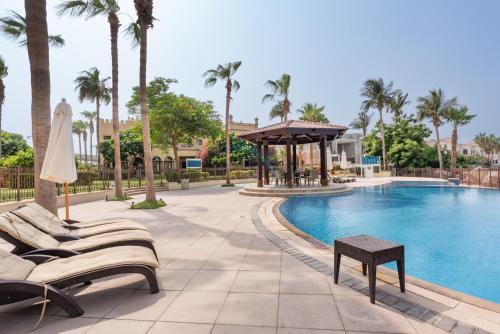 a pool at a resort with chairs and a umbrella at Luxury Beachfront Villa with Direct Beach Access, Next to Community Pool, Close to the Thrills of Aquaventure Waterpark, Canal Cove, Palm Jumeirah by Deluxe Holiday Homes in Dubai