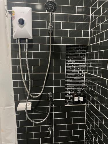 a black tiled bathroom with a shower with a hose at Urban Ease Hatyai in Hat Yai