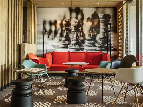 a living room with a red couch and tables at ibis Sens in Sens