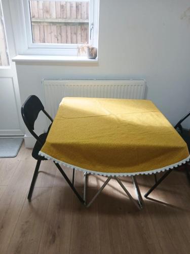 a table with a yellow blanket on top of it at Attractive 3 bed house in London Harrow in Harrow