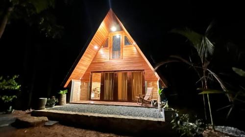 a wooden house at night with a bench in front at Siri Villa Cabana Habaraduwa in Habaraduwa