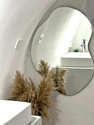 Petuna Cave Suites في فيرا: حمام مع مرآة مستديرة على الحائط