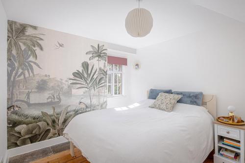 スタンステッド・マウントフィーチェットにあるStylish 3-Bed Home Close to Stansted Airportのトロピカルな壁紙の白いベッドが備わるベッドルーム1室が備わります。