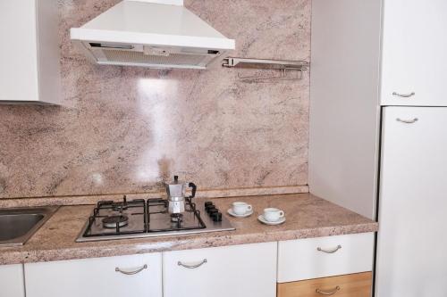 a kitchen with a stove and a sink at Cozy flat in a bright residence-Beahost in Rosolina Mare